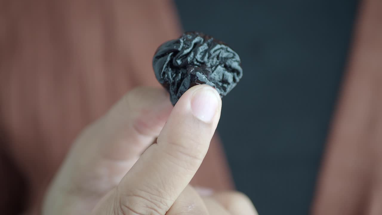 cerca de una sola ciruela sostenida entre los dedos