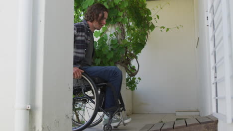 caucasian disabled man in wheelchair entering door of his house