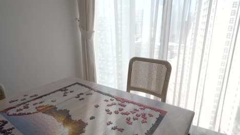 large picture puzzle partially put together in a an apartment dining room - pullback reveal - concept: give up, stop trying, undone, unsolved, incomplete, goal