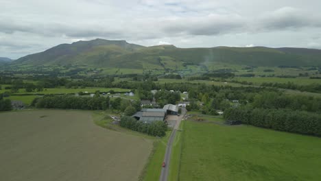 Flug-über-Bauernhof-Und-Campingplatz-In-Richtung-Berg-Blencathra-An-Einem-Bewölkten-Sommertag