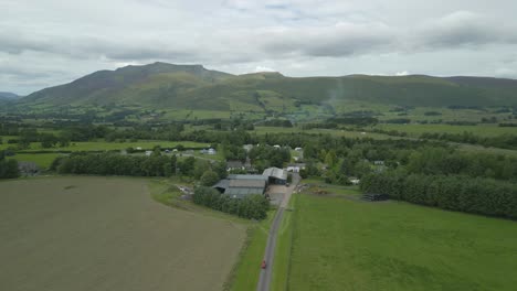 flying over farm and campsite towards mountain blencathra on cloudy summer day