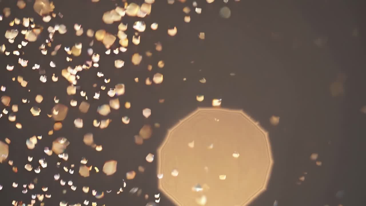 A dreamy, abstract video with a close-up angle, capturing soft, golden bokeh lights floating
