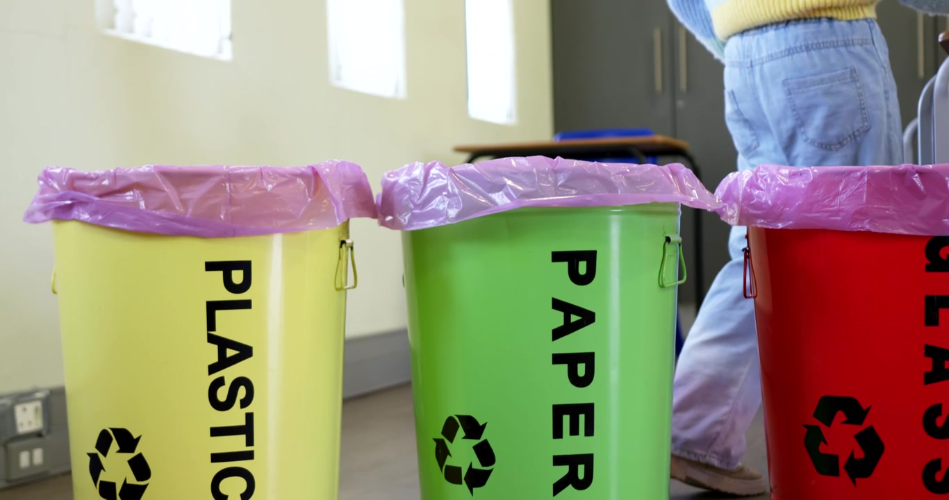 African American youth at school carrying paper, dropping into green PAPER bin to recycle, walking