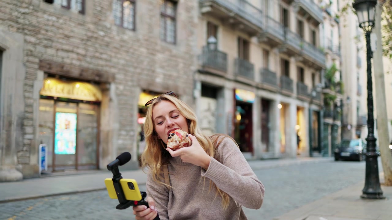 Giovane donna felice che fa vlogging e mangia pizza all'aperto