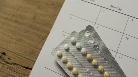 video of close up of yellow tablets over calendar on wooden table