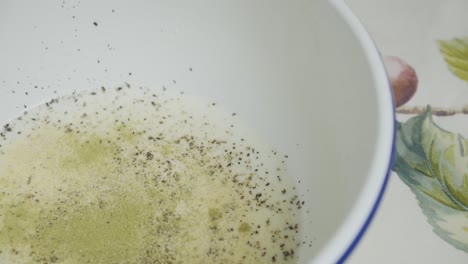 adding spices to butter milk inside white deep plate