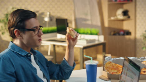 hablando colegas comiendo pizza para el almuerzo en primer plano. dos diseñadores bebiendo cola