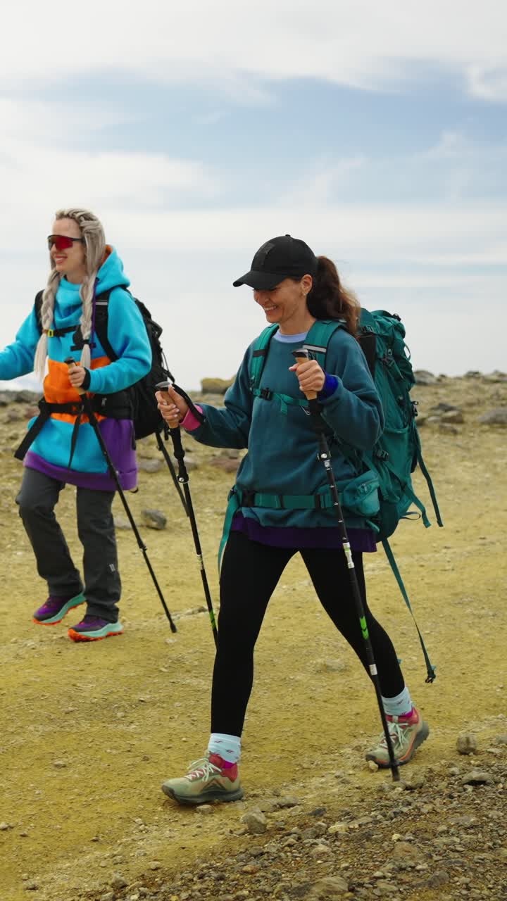 Due donne che fanno escursioni con zaini e bastoncini da trekking su un sentiero di montagna
