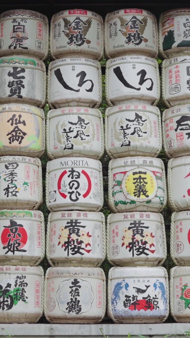 Vertical wide video of colorful and beautiful sake barrels at Meiji Jingu Shrine during the daytime in Yoyogi Park in Tokyo.