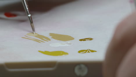 close up of artist mixing different color paints on palette to create unique colors for painting