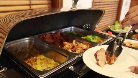 person serving various foods onto a plate