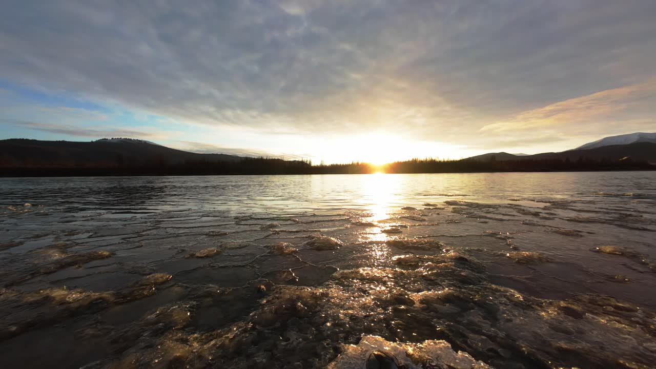 Sunset over a frozen river with mountains in the background