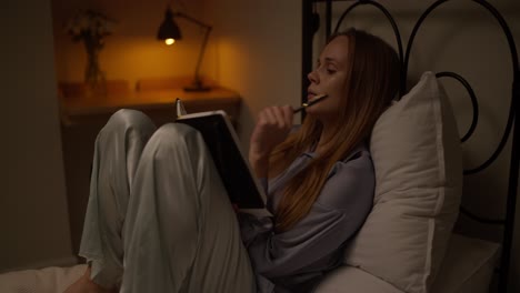 woman writing in a journal in bed at night