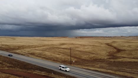 areal drone shot of isolated road through empty golden fields on a dark, overcast day