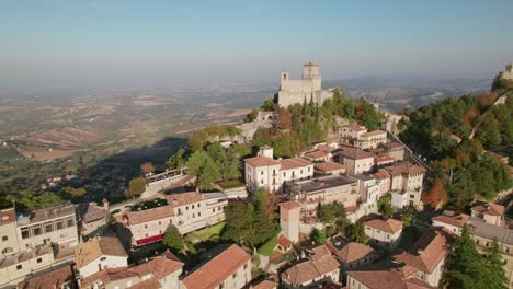 Three-Towers-of-San-Marino,-Italy,-close-pull-in-drone-view-during-sunset