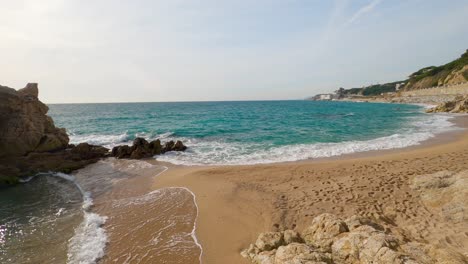 Schöner-Mediterraner-Sandstrand,-Maresme-Barcelona,-San-Pol-De-Mar,-Mit-Felsen-Und-Ruhigem-Meer-Und-Türkis