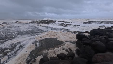storm clouds at snapper rocks with foamy waves crashing. tropical cyclone alfred in queensland, australia. panning shot