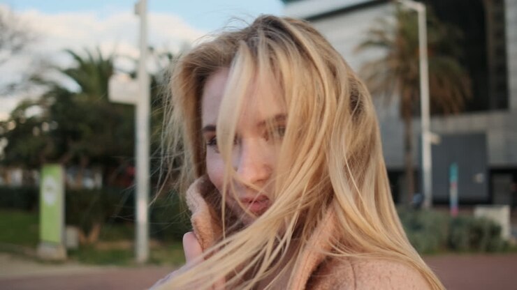 junge frau, die ihr gesicht mit einem mantel bedeckt.