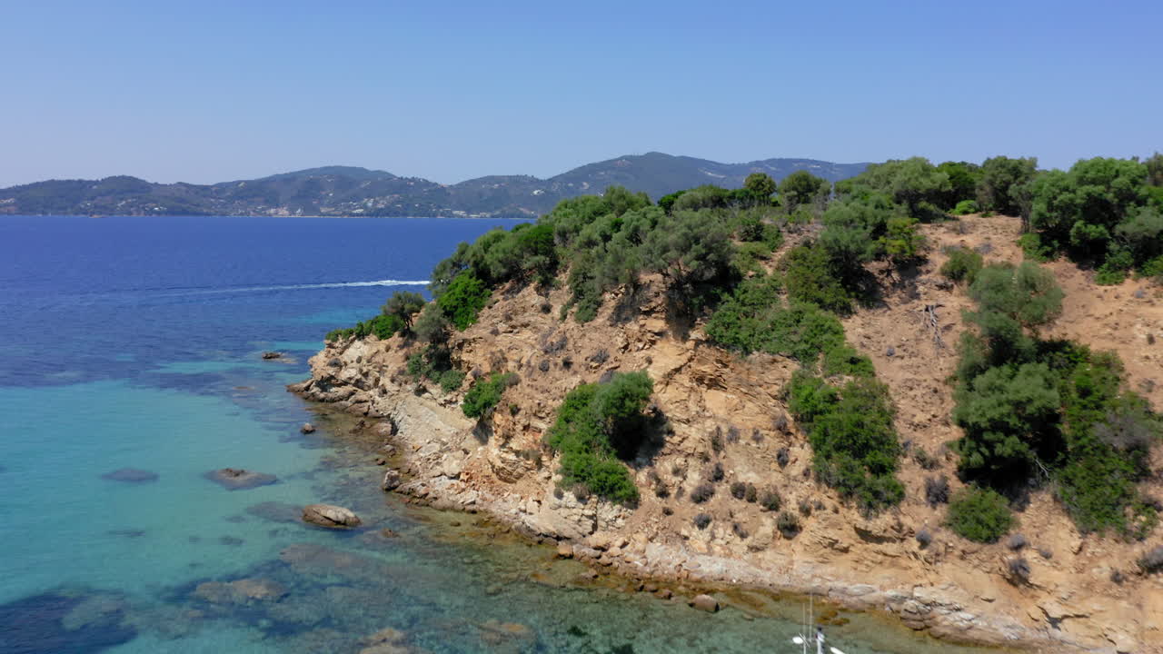 Aerial: Flying over a moored tourist boat in Tsougkria island beach near Skiathos on a sunny day