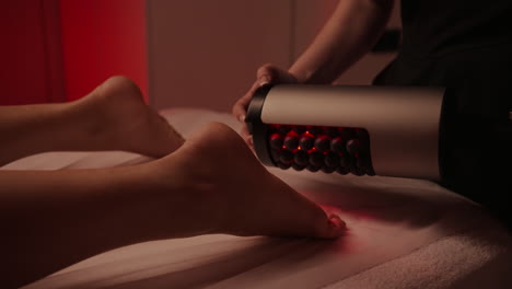 mujer recibiendo un masaje de pies de terapia de luz roja en un spa