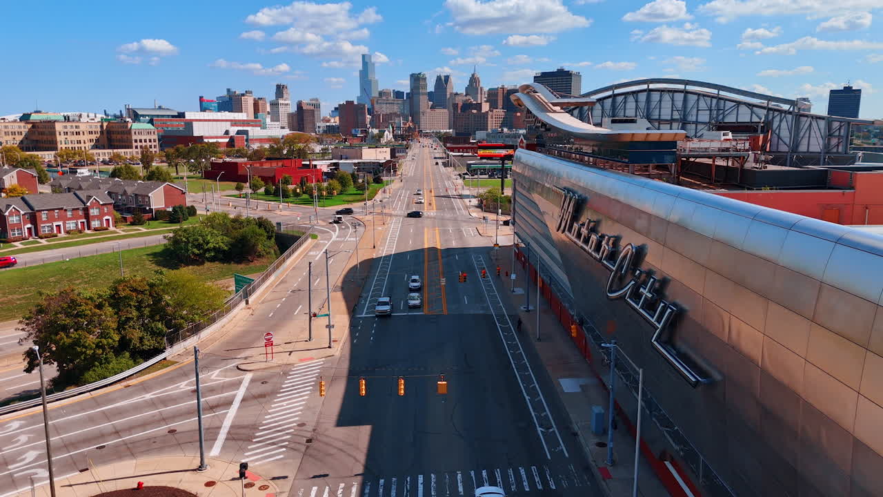 Detroit, USA, 28 July 2025: Downtown Detroit street by arena wall. Long straight avenue runs toward the Detroit skyline beside the sleek metal arena facade