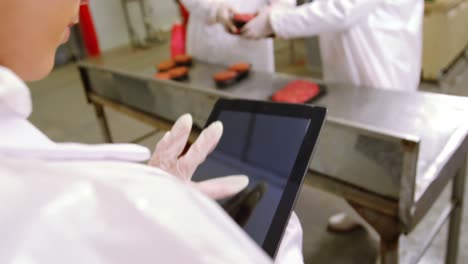 female butcher using digital tablet