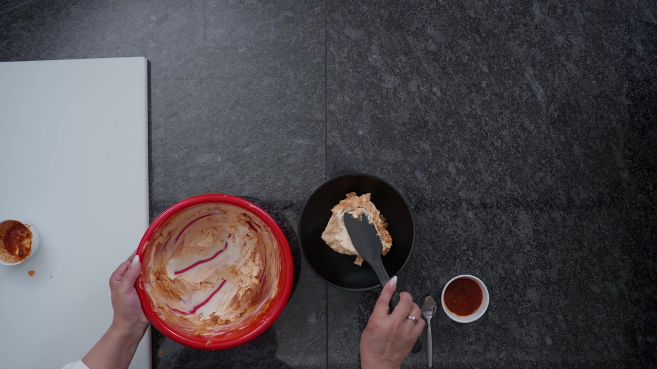 Chef plating a creamy dish in a commercial kitchen. Food preparation footage showing catering, cooking and hospitality concepts in a professional kitchen setting, top-down close-up