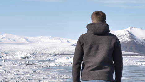 Young-Blond-Male-Traveler-Walking-Towards-Glacial-Lagoon-in-Iceland