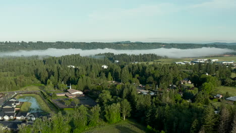 Drone-dolly-shot-of-a-small-country-town-with-fog-within-the-forest