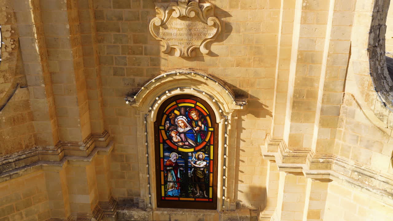 Buntglasfenster in einer Steinmauer in der Ta Pinu Basilika, Insel Gozo, Malta. Luftaufnahme.