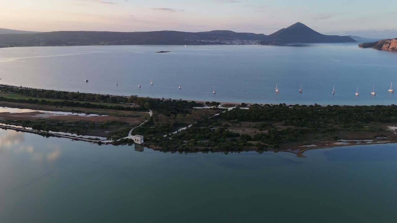 Navarin,Messinia,Aerial view circle pan right from Giolova Lagoon and Beach towards mountains during sunrise.Beautiful panoramic scenery of mountains,reflection of sun and clouds over the lagoon