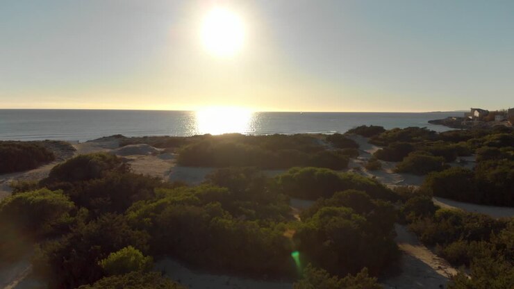 Paisagem de praia ao pôr do sol com dunas de areia