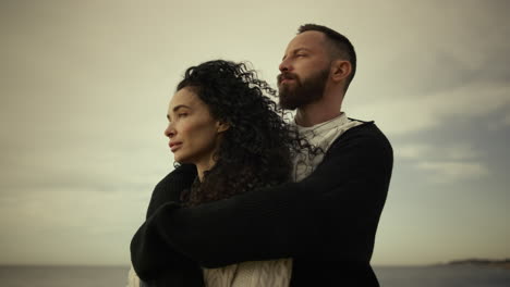 young couple embracing together on seaside beach. two lovers enjoy calm vacation