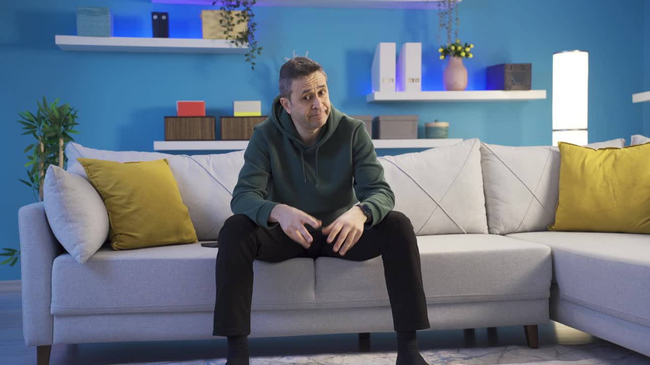 집에서 외로움을 겪고 있는 우울증에 걸린 남자가 무기력하고 기분이 좋지 않은 채 주변을 둘러보고 있습니다.