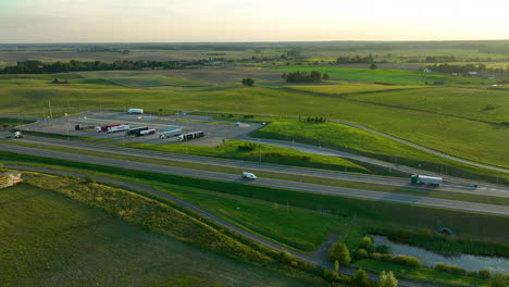 vista aérea de una intersección de carretera y área de descanso rodeada de campos verdes