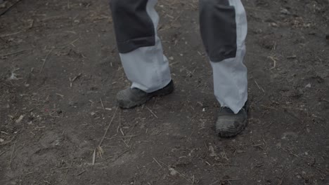 worker walks on a dirty ground in new white trousers