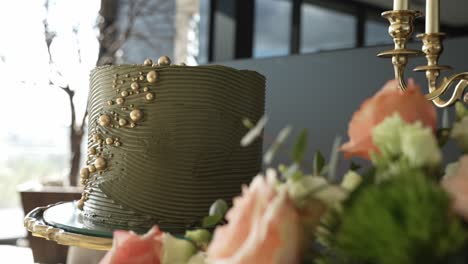 close up of an elegant olive green cake adorned with gold accents and floral decor