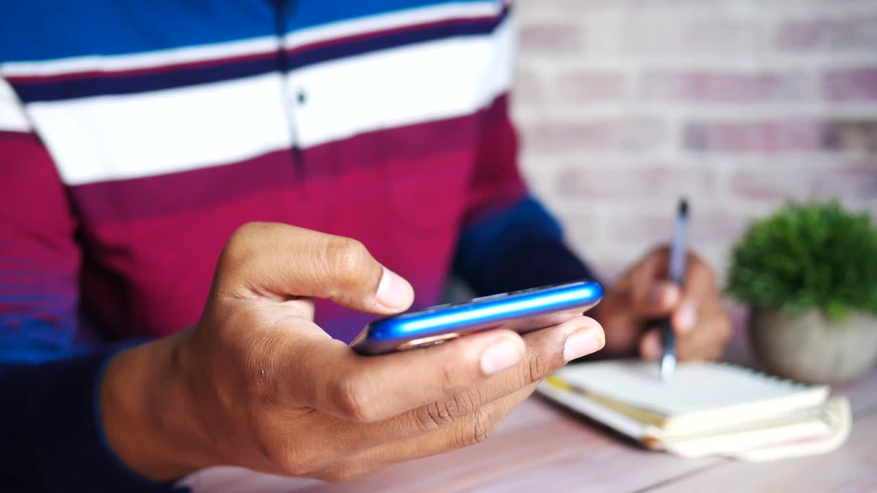 persona que utiliza un teléfono inteligente y toma notas