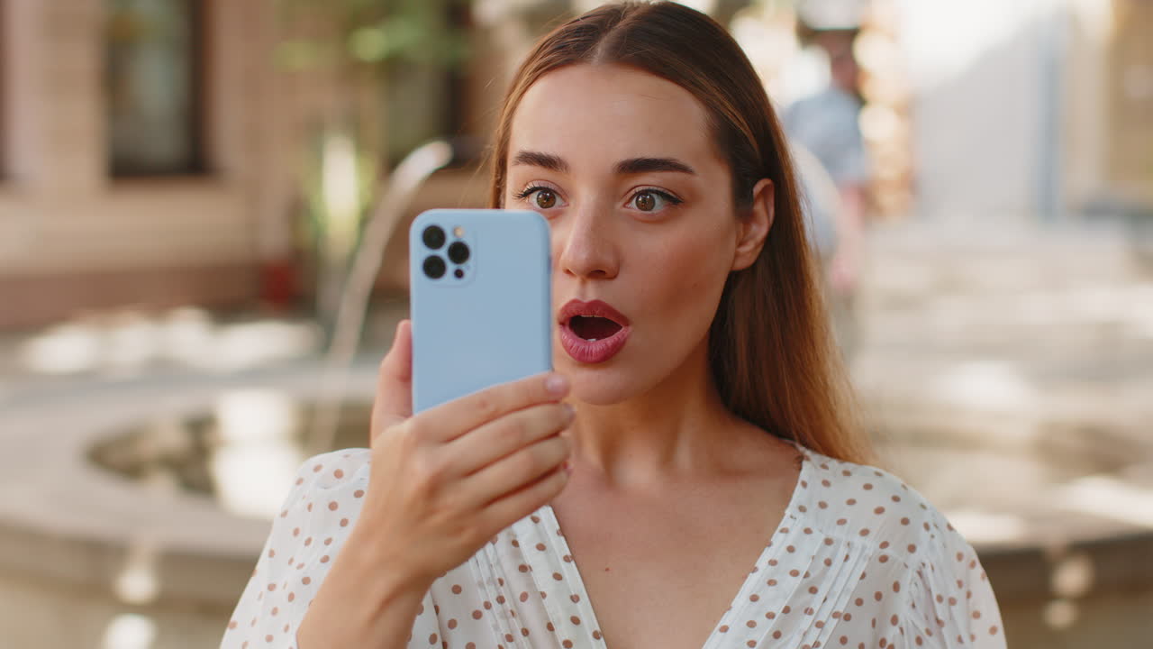 스마트폰을 사용하는 행복한 여성은 좋은 소식을 받습니다 도시 거리에서 와우 감정