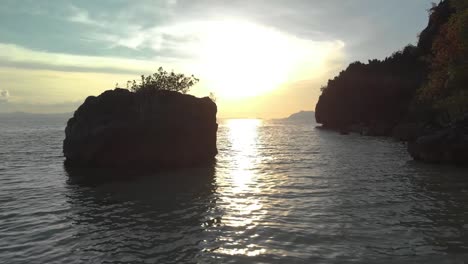 aerial drone shot flying low to ocean, between limestone cliffs and towards the sunset, at coron island, in philippines, asia