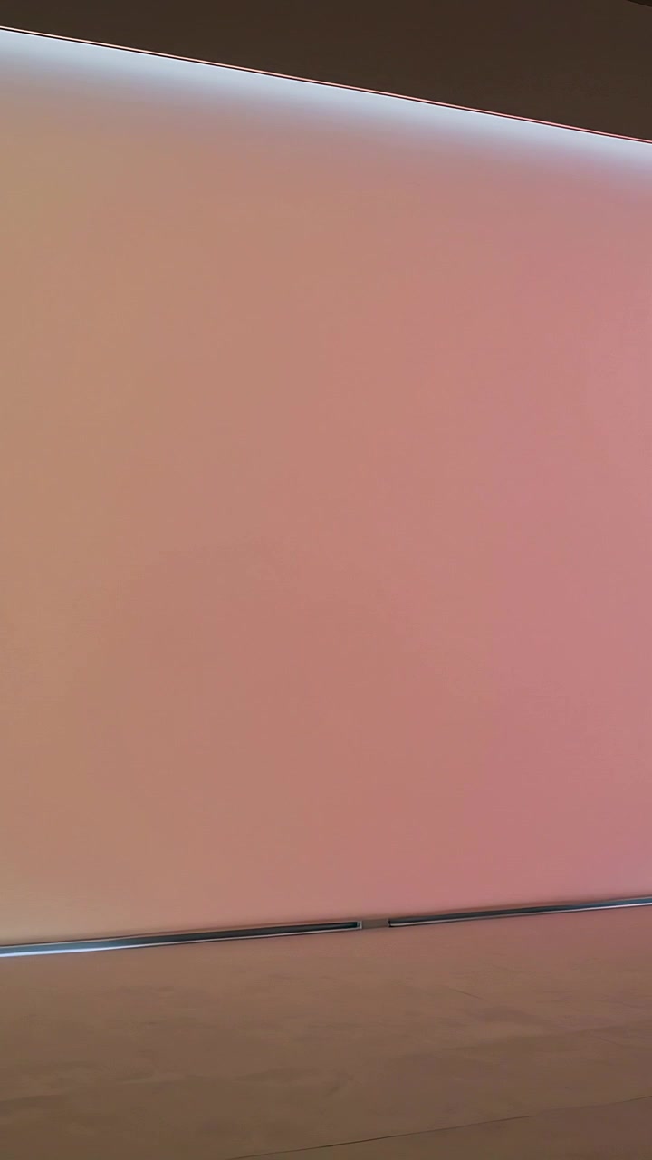 Vertical video: Lighting LED panel shifting white to warm pink in gallery above wood floor trim