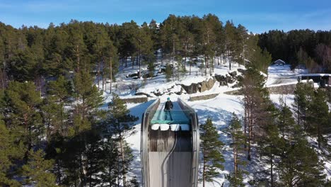 closeup to overview of man standing on edge of stegastein viewpoint - reverse aerial looking towards platform with fjord behind camera while moving backwards to reveal aurlandsfjellet mountain