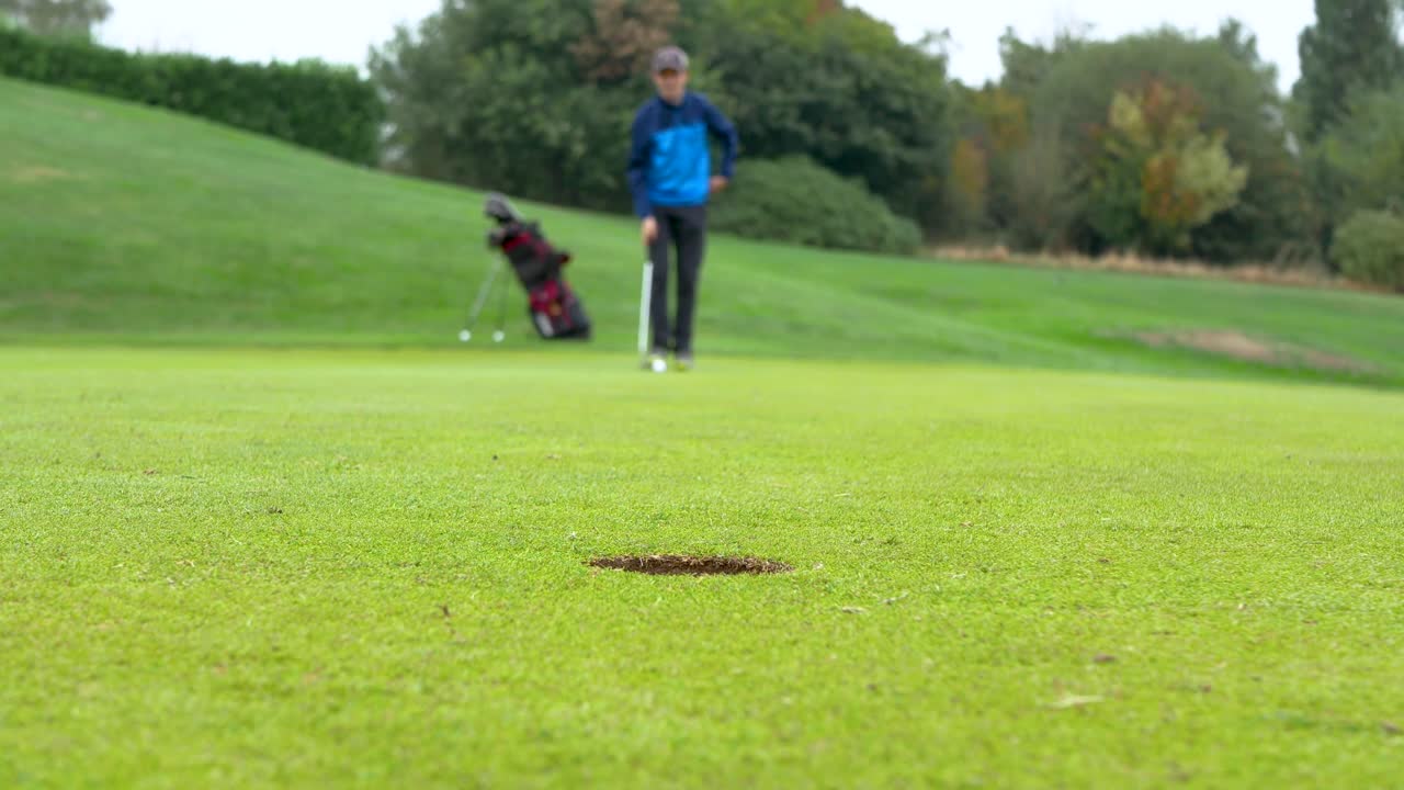golfista borroso pasando por su rutina de putt centrándose en el hoyo
