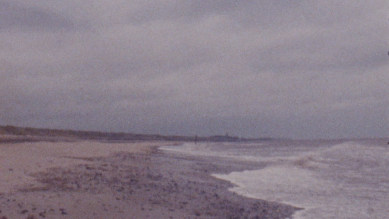 Super 8mm film no perforation scan of UK English Norfolk Coast beach seaside in stormy weather and waves crashing in foreground