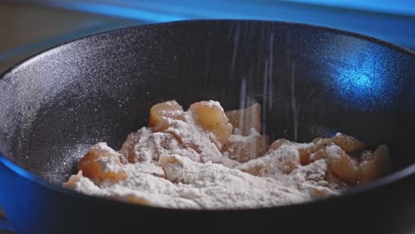 mixing flour on breast chicken meat cut into cubes with salt and pepper