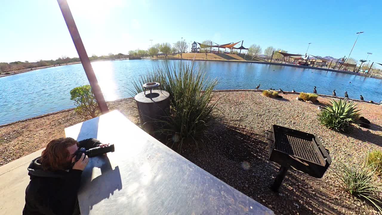 Red haired male photographing cormorants at Mansel Crater Park in Queen Creek Arizona.