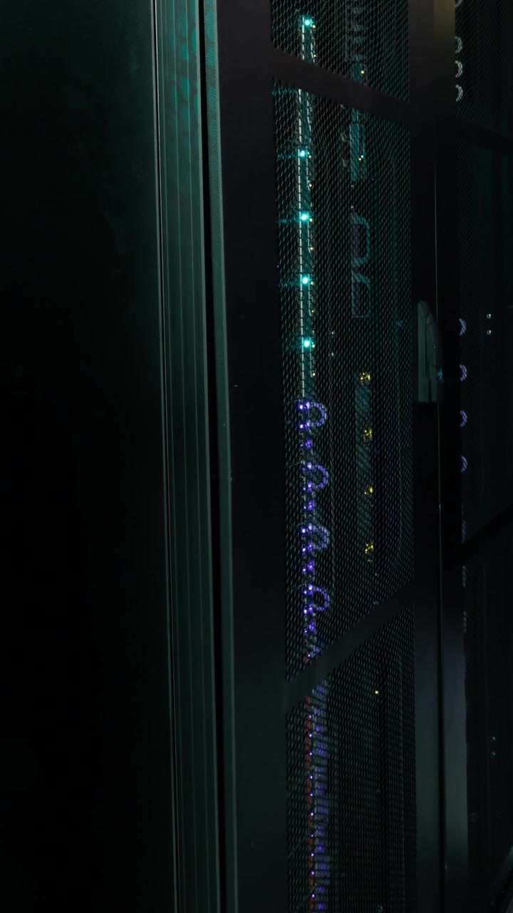 Video of empty corridor with rows of computer servers with green and purple lights