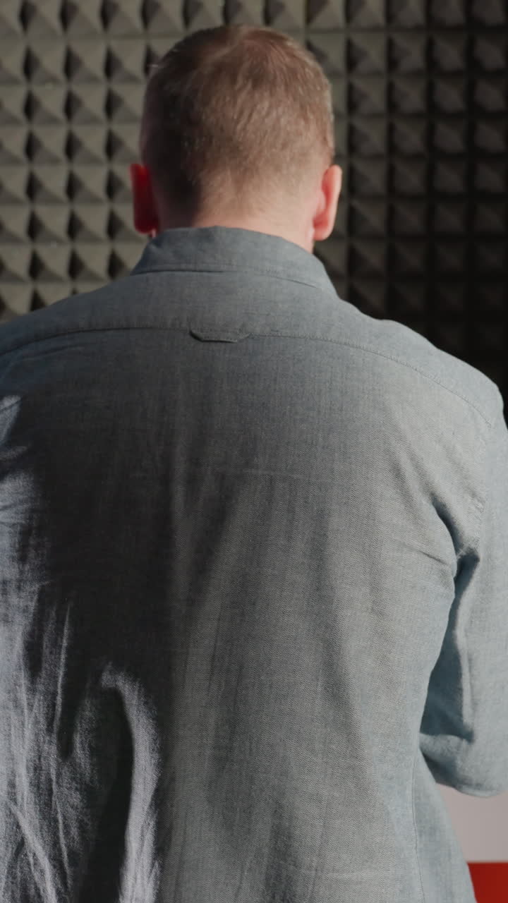 파란 셔츠를 입은 남자가  피아노를 연주하고, 그의 그림자가 검은색 음향 벽에 여있는 배경.