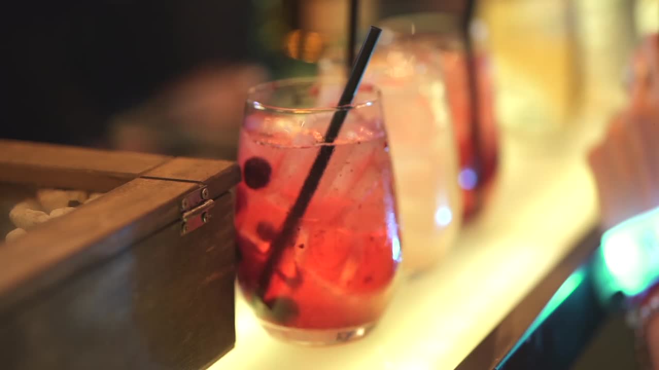Closeup at fruit cocktails in a bartender bar near women's hair at night, party event