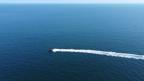 a fast rigid inflatable boat powers across the frame with nothing but sea and horizon, whilst leaving a long trail of wake and wash behind